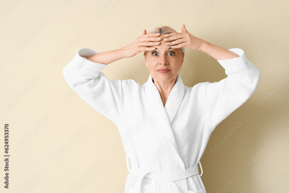 Mature woman doing face building exercise on beige background