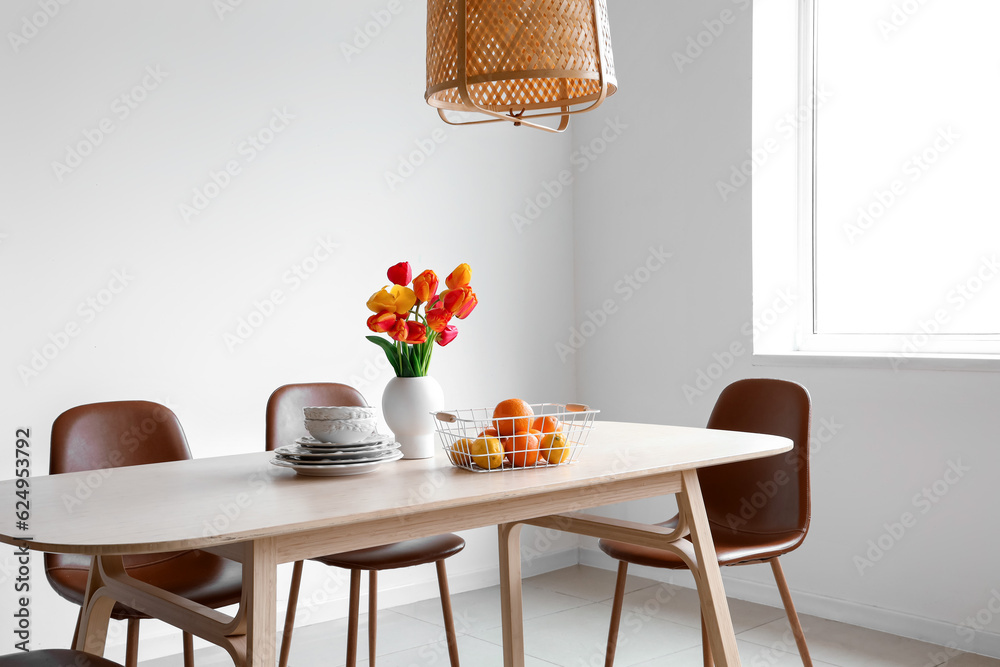 Interior of light dining room with tulip flowers on table