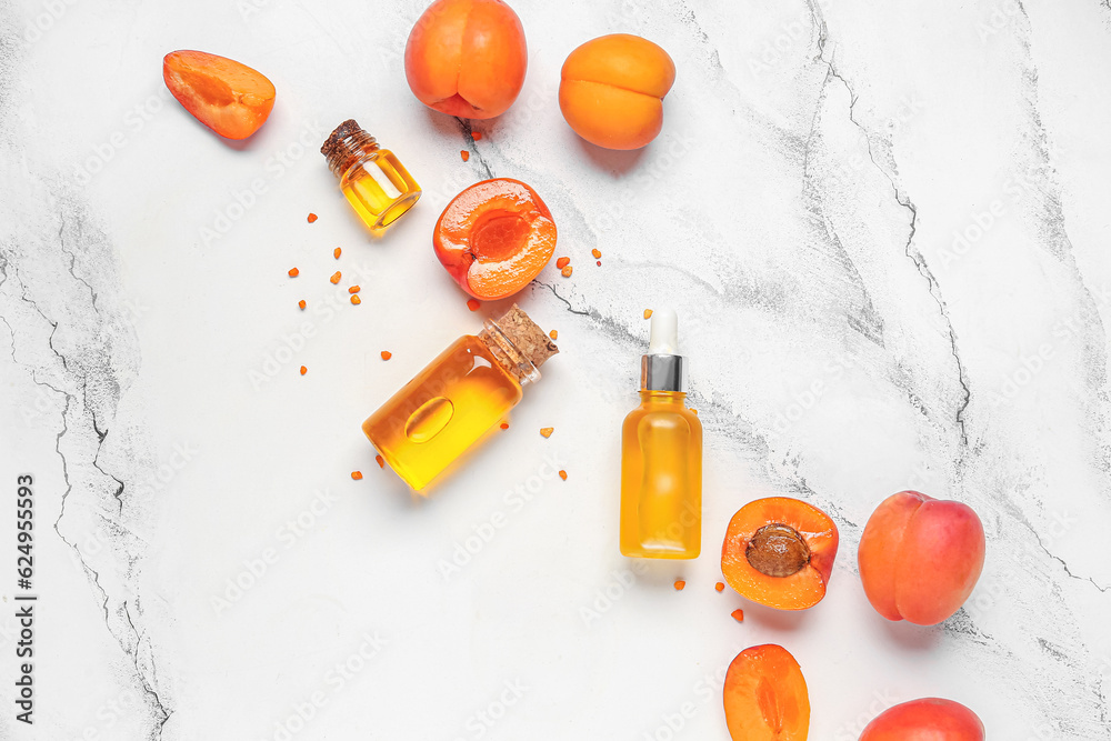 Composition with bottles of essential oil and ripe apricots on light background