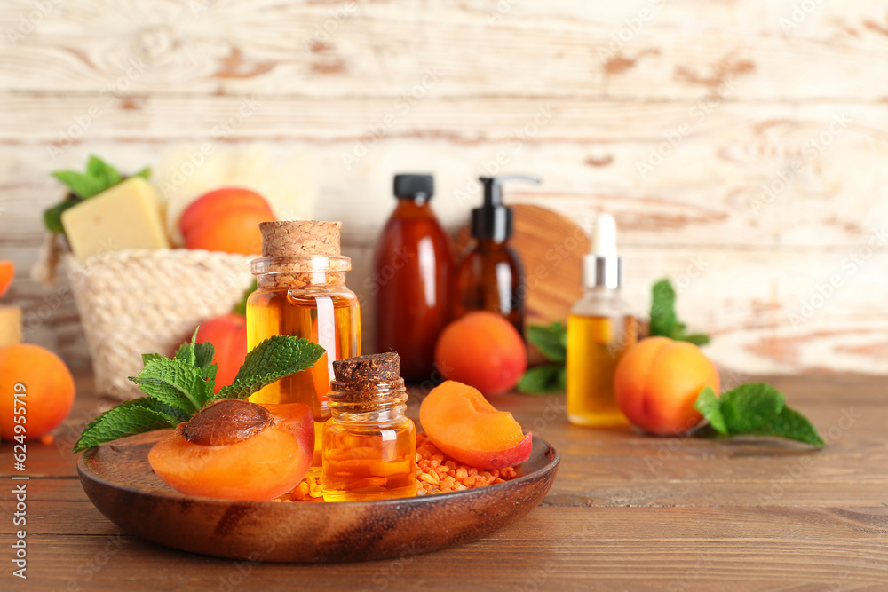 Bottles with cosmetic oil, sea salt and apricots on wooden table