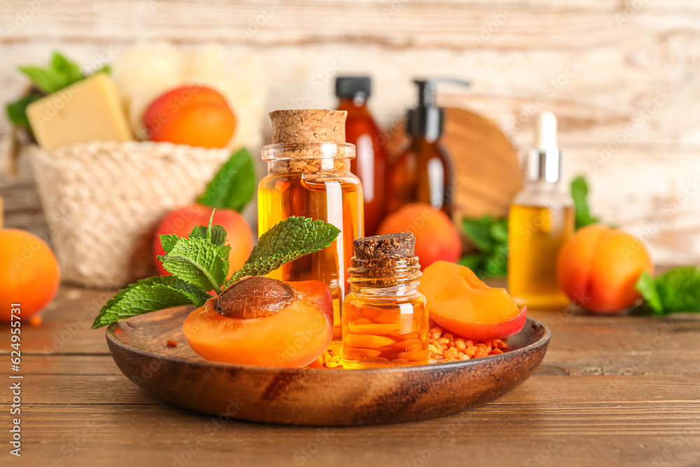 Bottles with cosmetic oil, sea salt and apricots on wooden table