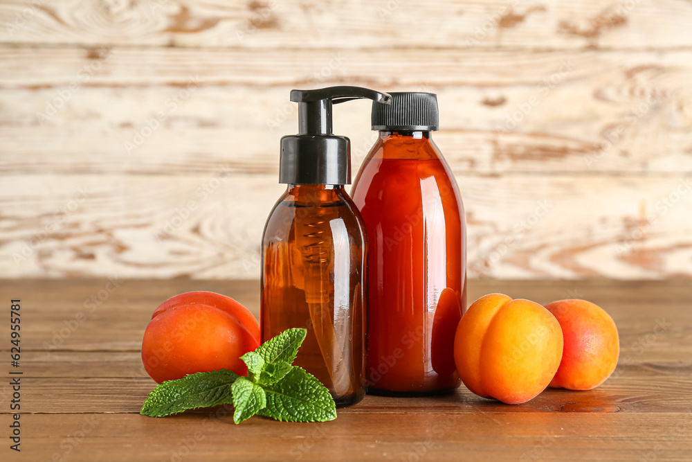 Bottles with cosmetic oil and apricots on wooden table