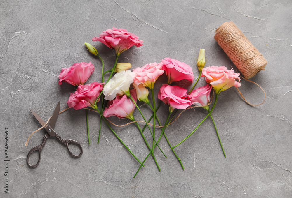 Beautiful pink eustoma flowers and threads on grey background