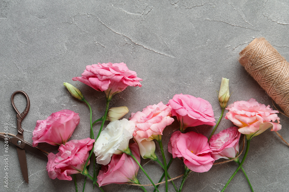 Beautiful pink eustoma flowers and threads on grey background