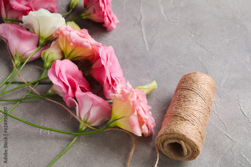 Beautiful pink eustoma flowers and threads on grey background