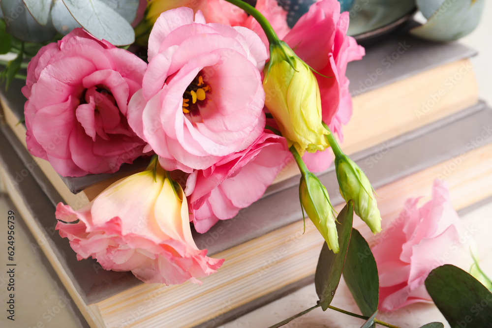 Beautiful pink eustoma flowers with eucalyptus and books, closeup