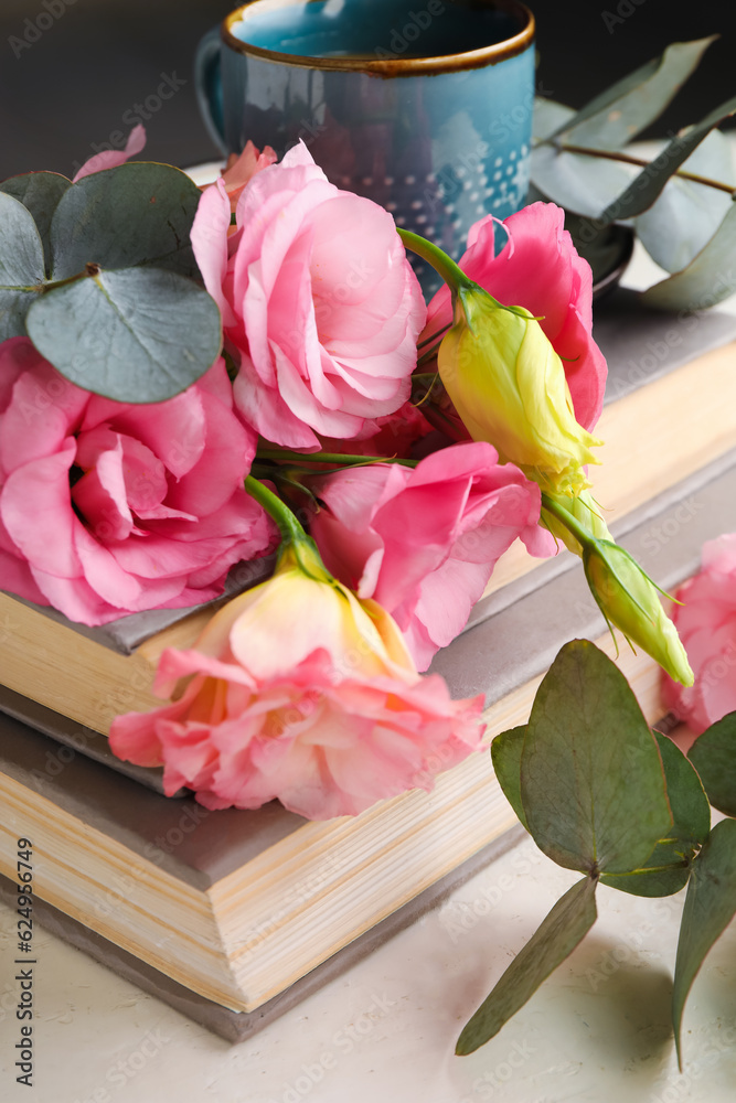 Beautiful pink eustoma flowers with eucalyptus, books and cup of coffee, closeup