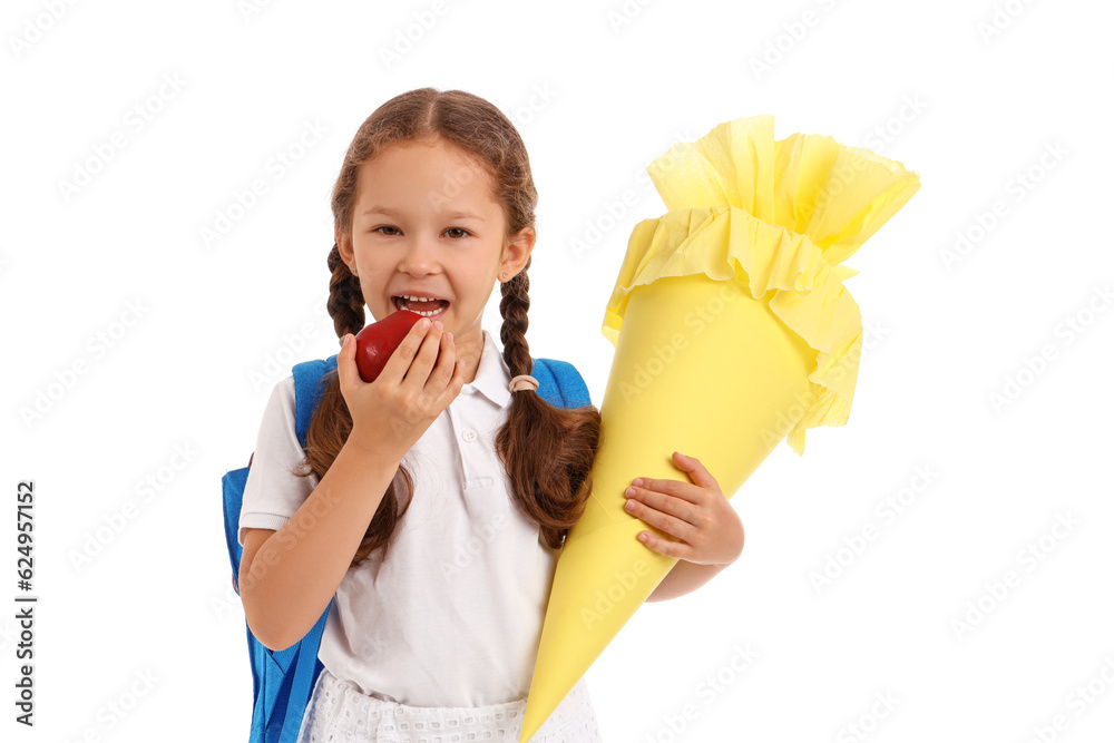 Little girl with backpack and yellow school cone eating fresh apple on white background