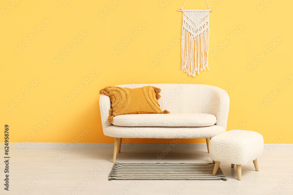 Cozy white sofa and ottoman near orange wall with wicker decor