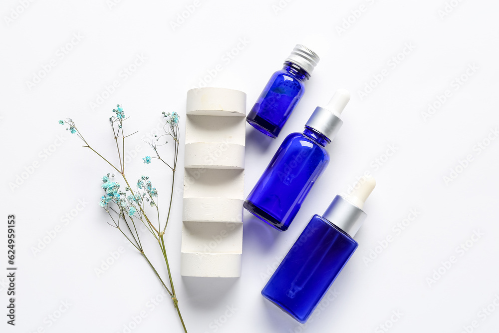 Composition with bottles of cosmetic products, plaster decor and gypsophila flowers on light backgro