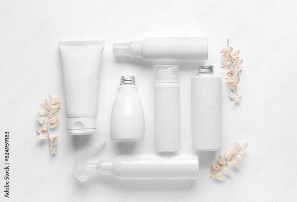 Composition with different cosmetic products and dried plants on light background