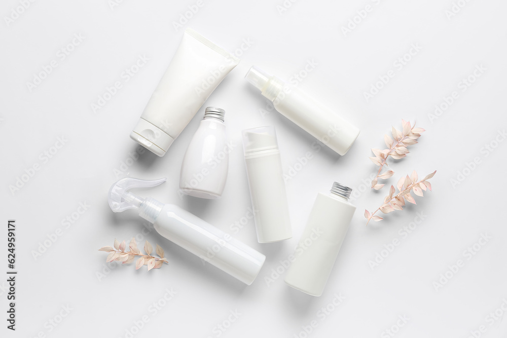 Composition with different cosmetic products and dried plants on light background