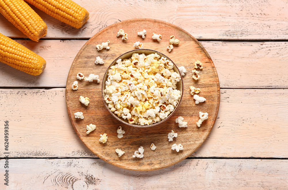 Bowl with tasty popcorn on white wooden background