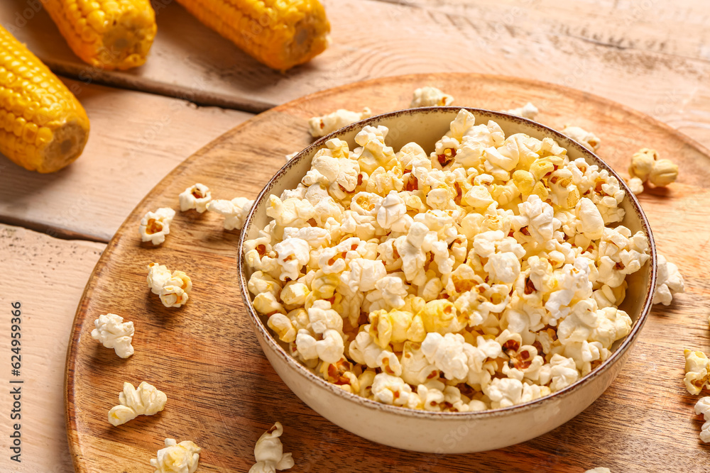 Bowl with tasty popcorn on white wooden background