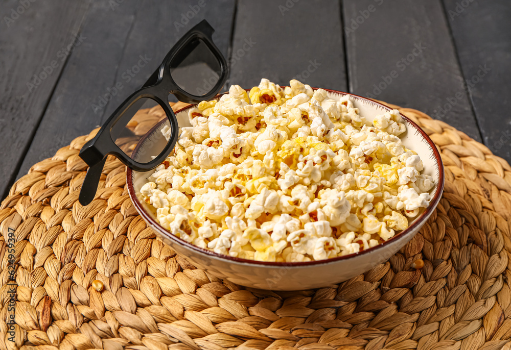 Bowl with tasty popcorn and 3D glasses on black wooden background