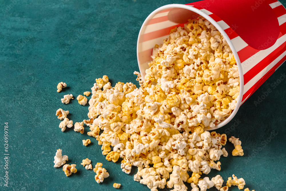 Bucket with tasty popcorn on green background