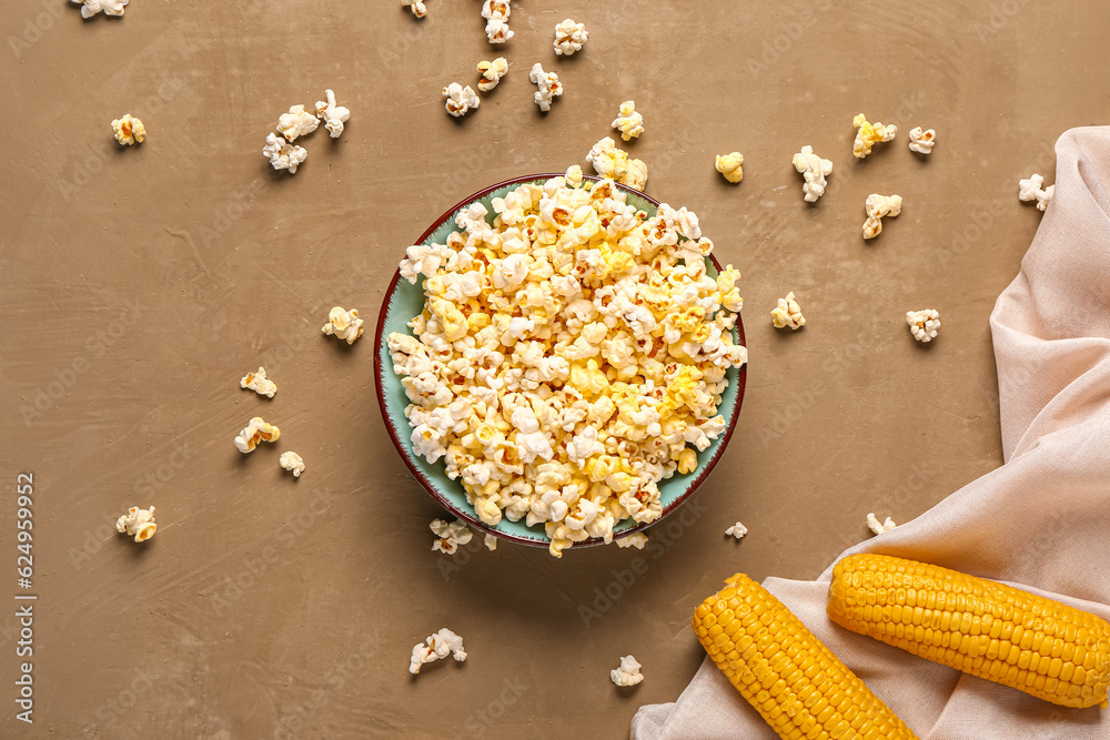 Bowl with tasty popcorn on brown background