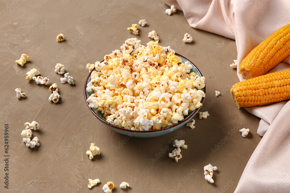 Bowl with tasty popcorn on brown background