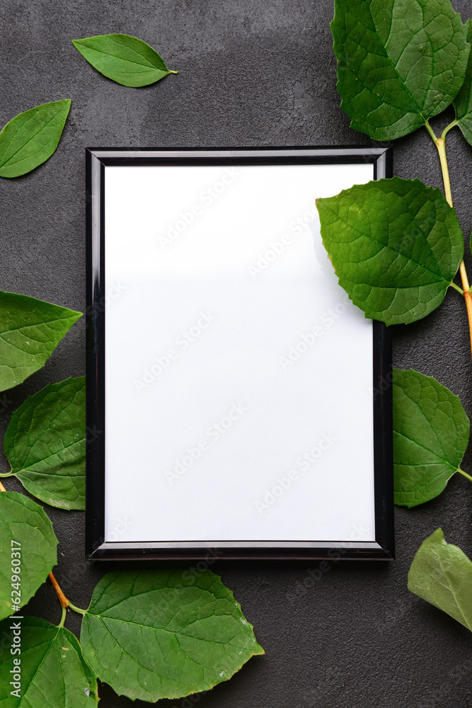 Blank photo frame and leaves on black background