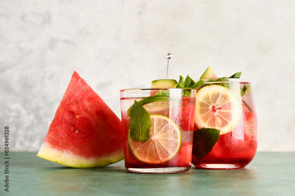 Glasses of fresh watermelon lemonade with mint on green table