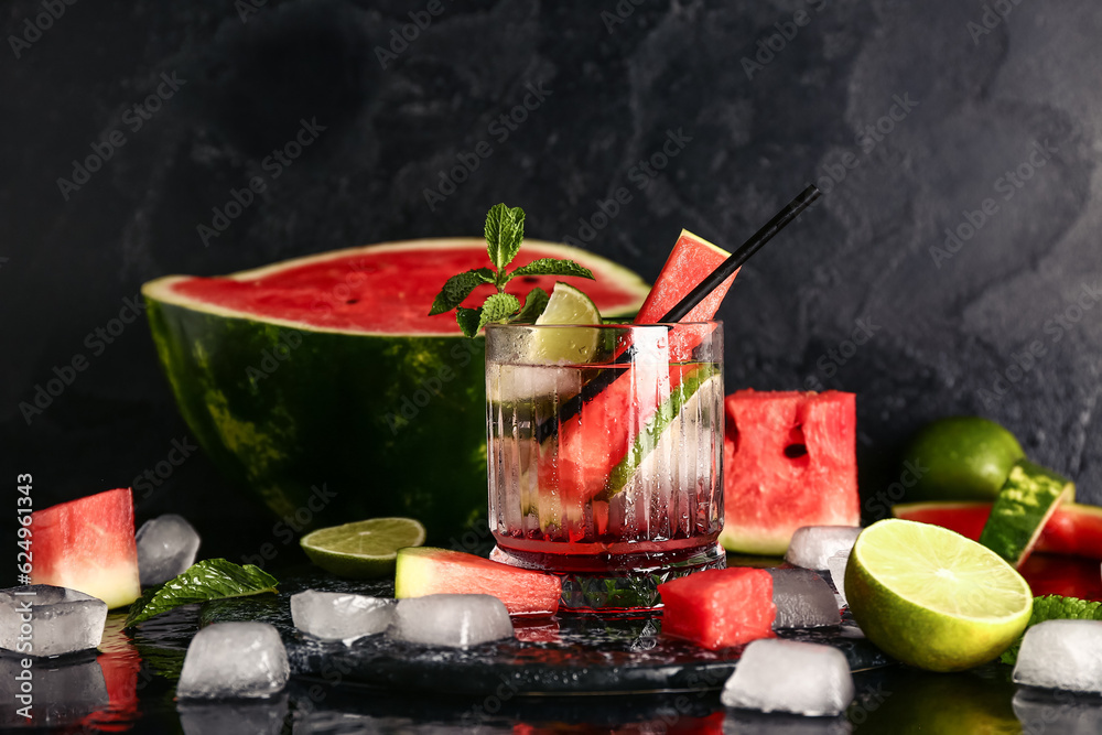 Glass of fresh watermelon lemonade with lime and mint on black background