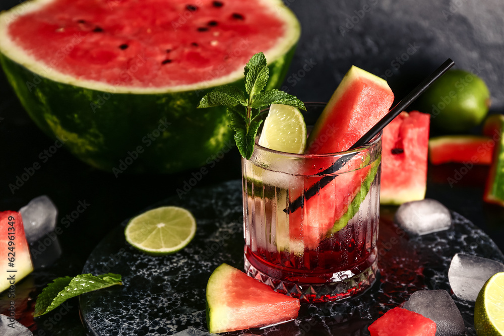 Glass of fresh watermelon lemonade with lime and mint on black background