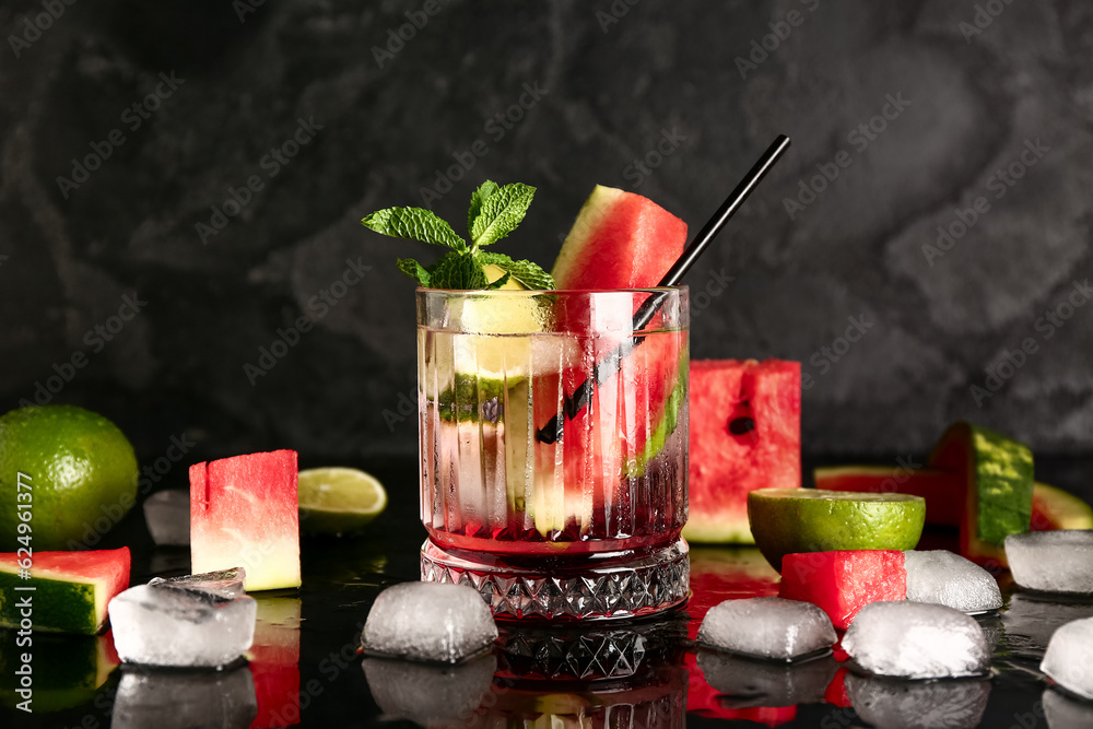 Glass of fresh watermelon lemonade with lime and mint on black background