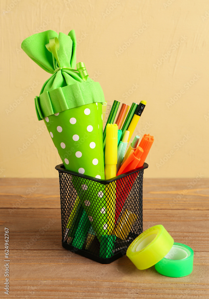 Green school cone and stationery on wooden table