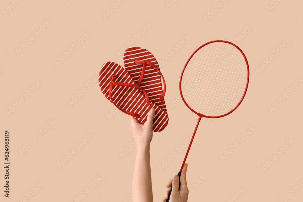 Female hands with flip flops and badminton racket on beige background