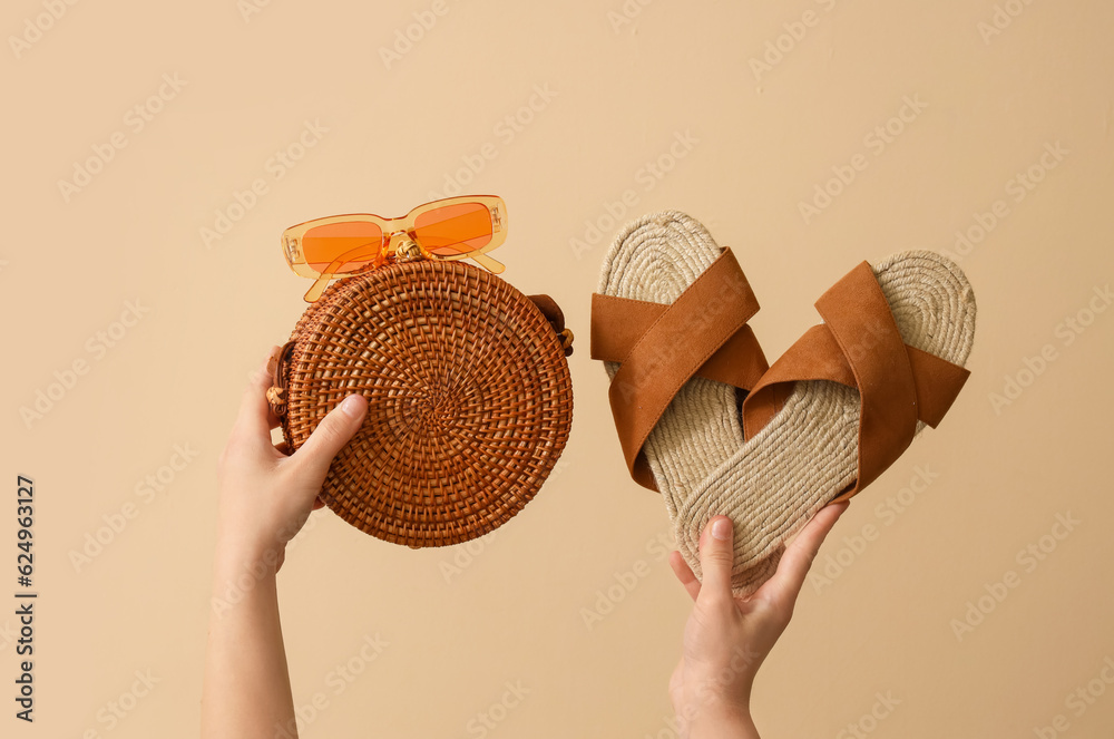 Female hands with beach accessories on beige background