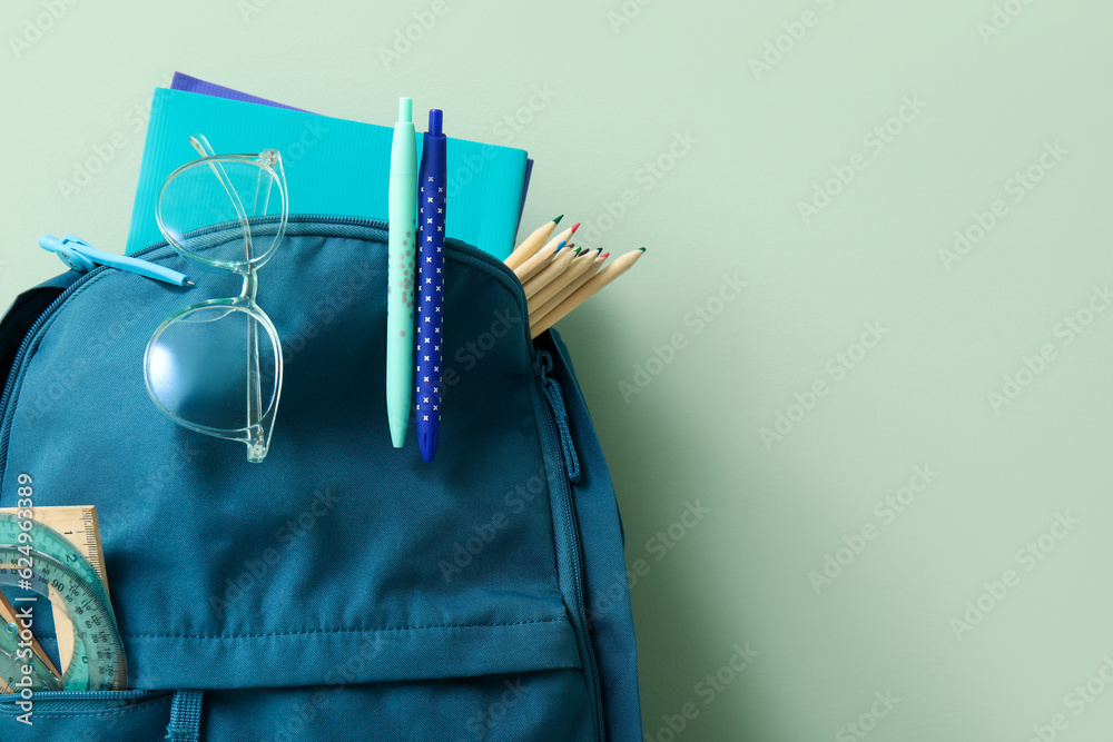 Blur school backpack with different stationery on pale green background