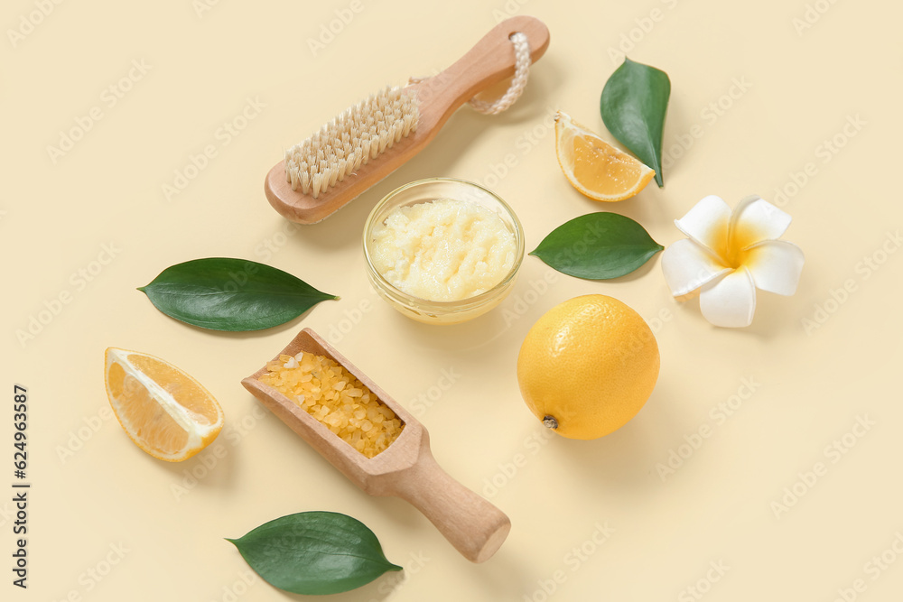 Bowl of lemon body scrub with massage brush and sea salt on pale yellow background