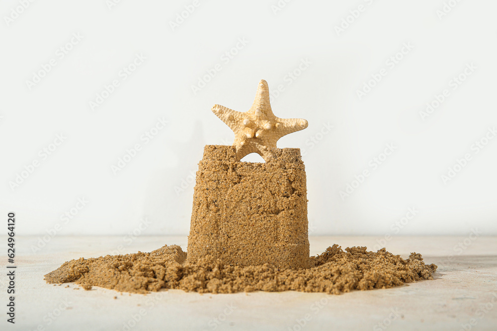 Castle made of sand with starfish on white background