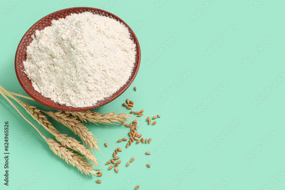 Wheat flour in bowl and spikelets on turquoise background