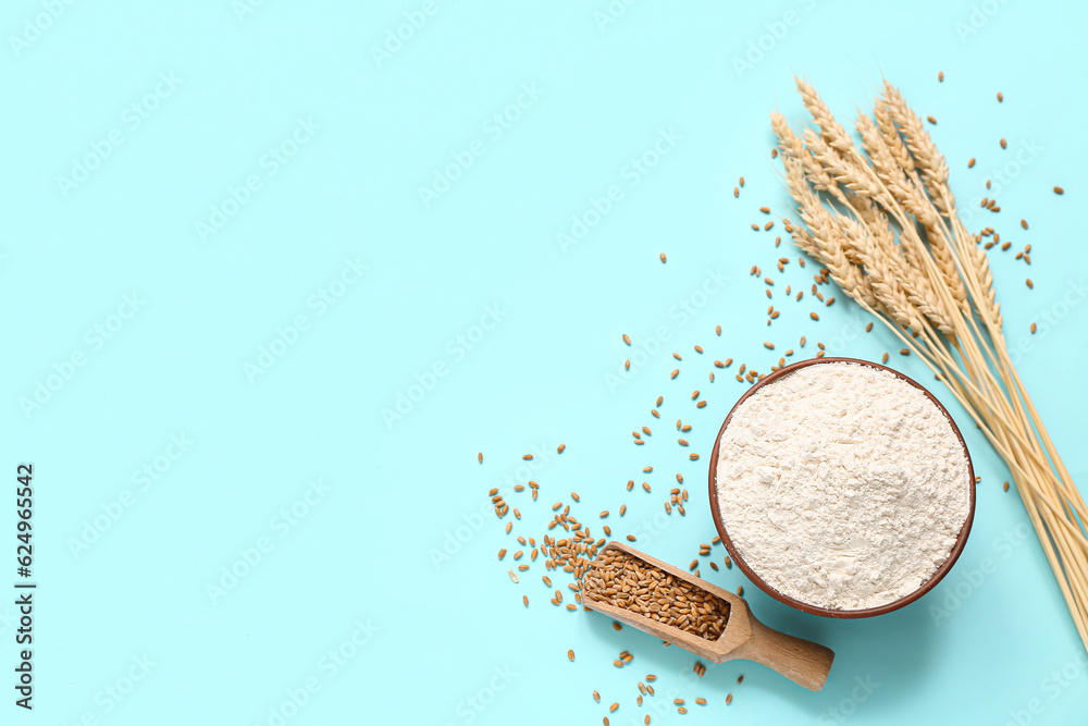 Bowl with wheat flour and spikelets on blue background