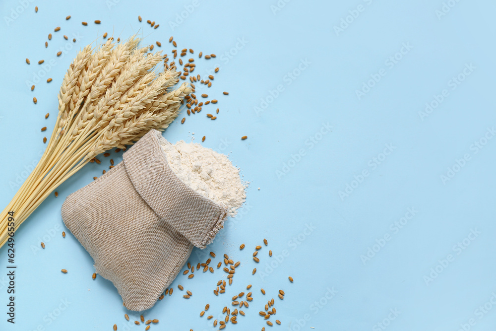 Sack with wheat flour and spikelets on blue background