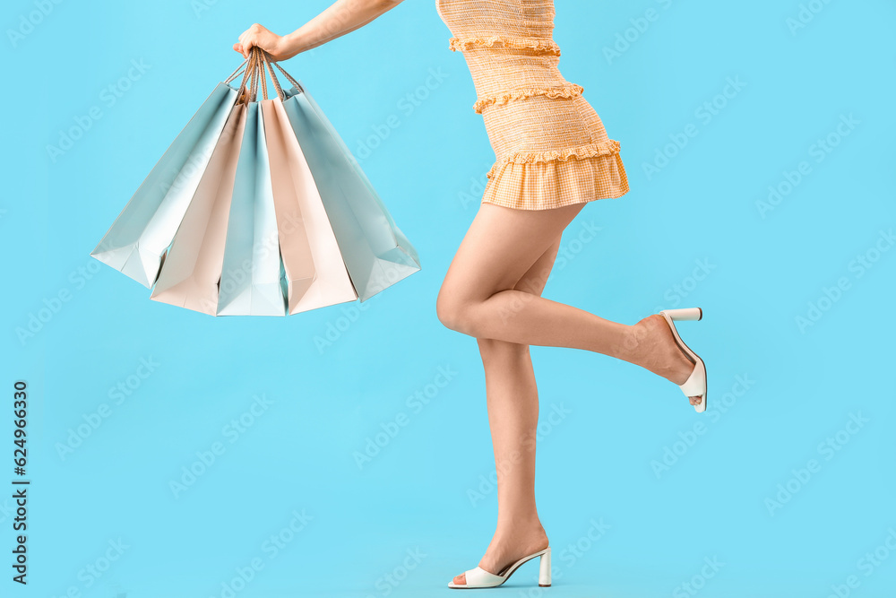 Beautiful young woman with shopping bags on blue background