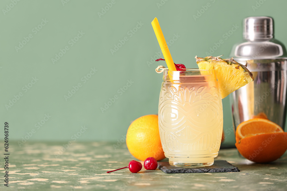 Glass of tasty mai tai cocktail on green background