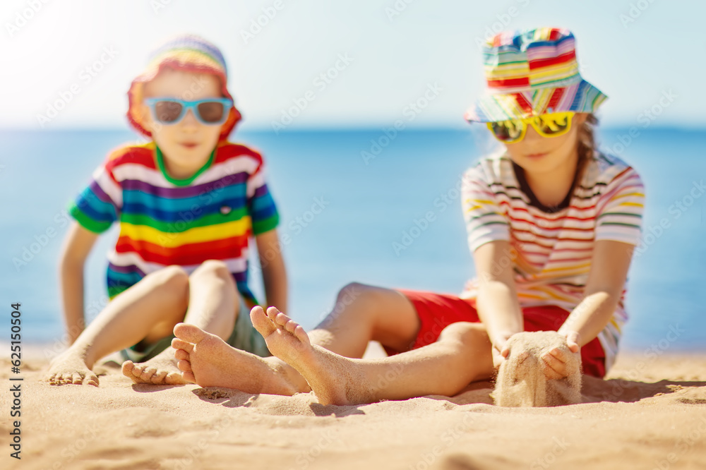 Boy and girl sitting on the sand near the sea.