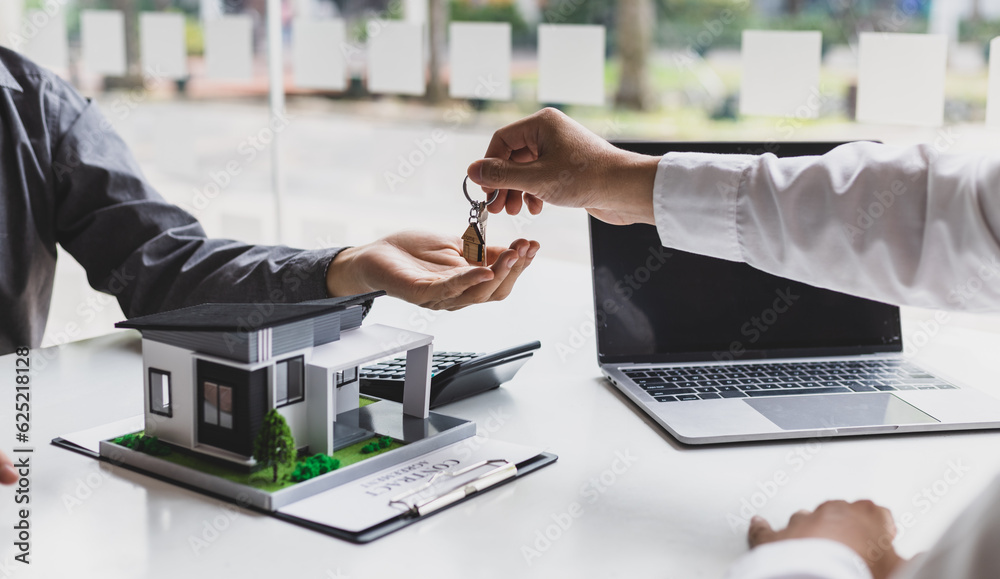 Real estate agent hands over the house keys to a homebuyer after the purchase agreement has been sig