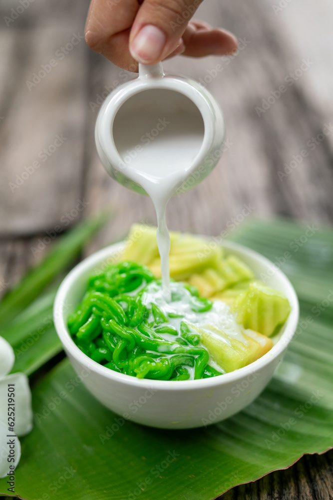 Lod Chong being poured with fresh coconut milk on banana leaf on wooden background