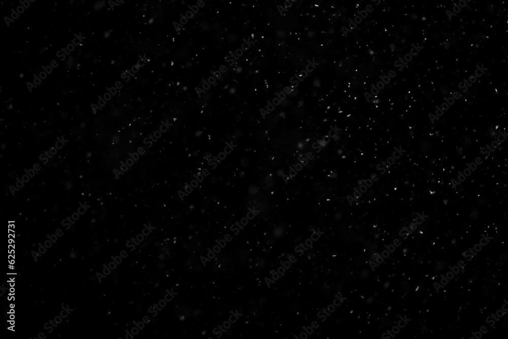 White snow falling in black night sky in the dark