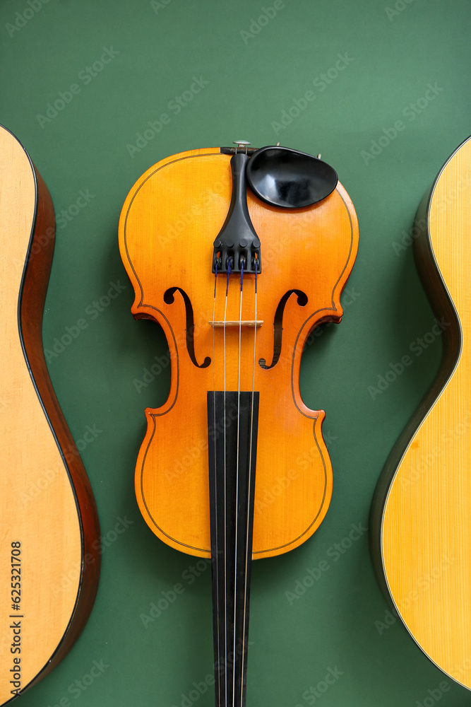 Acoustic guitars and violin on color background