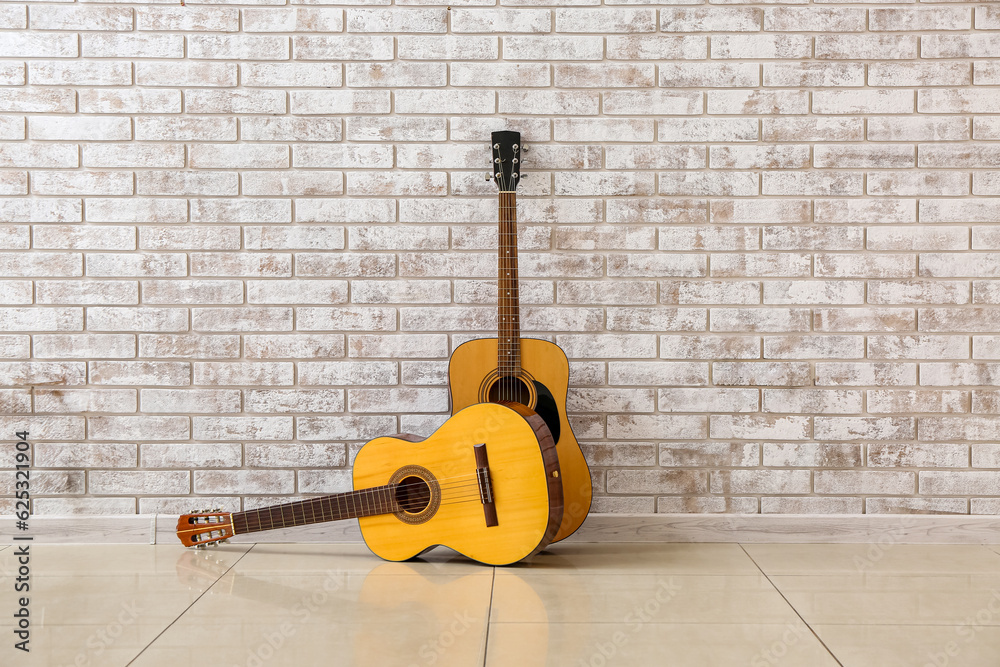 Two guitars near brick wall