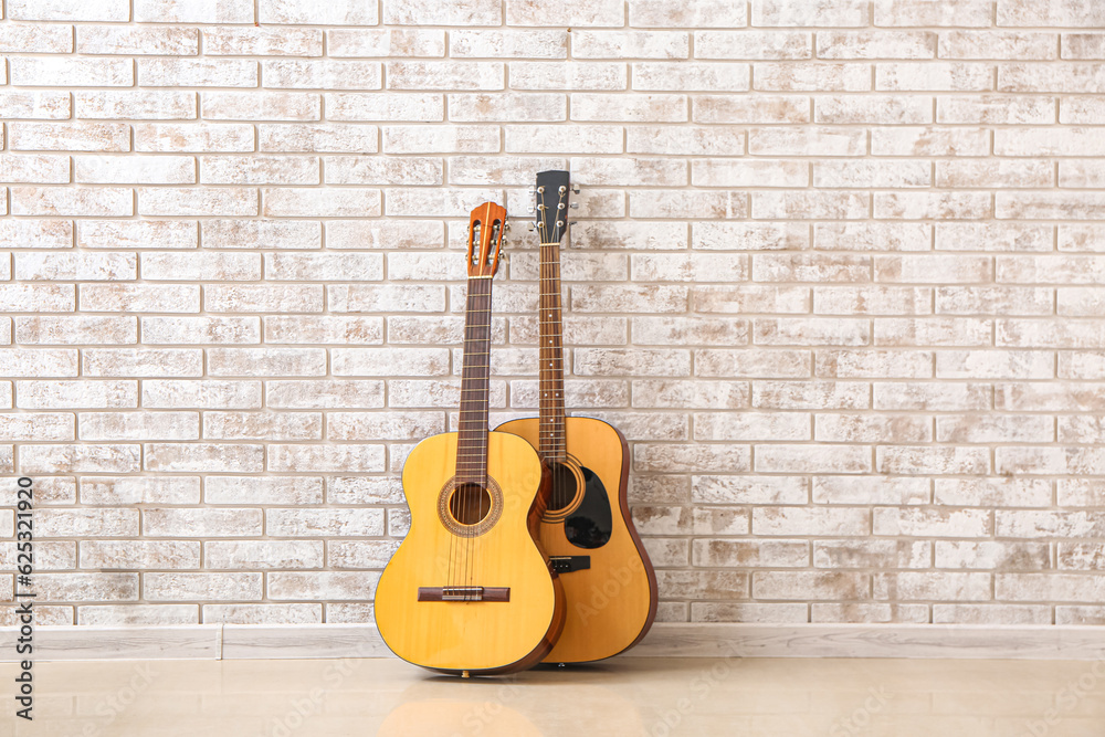 Two guitars near brick wall