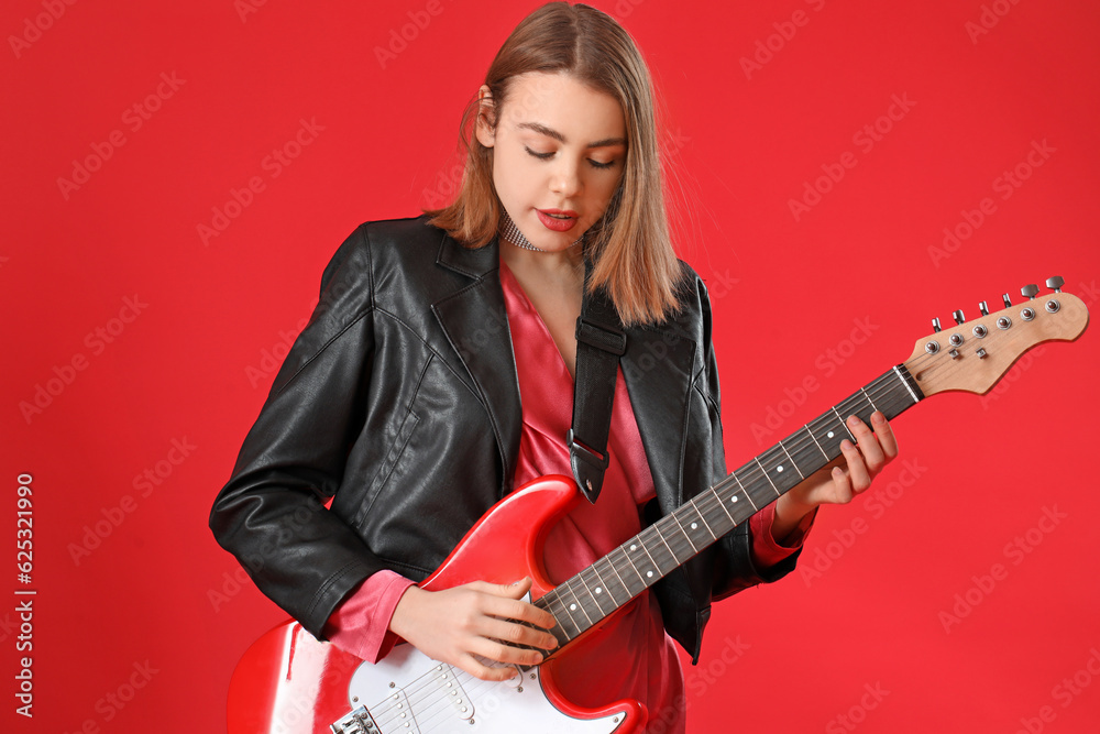 Young woman playing guitar on red background