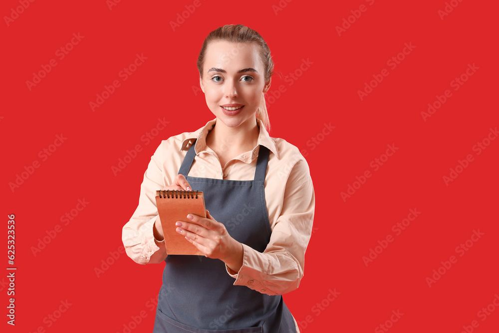 Young barista with notebook on red background