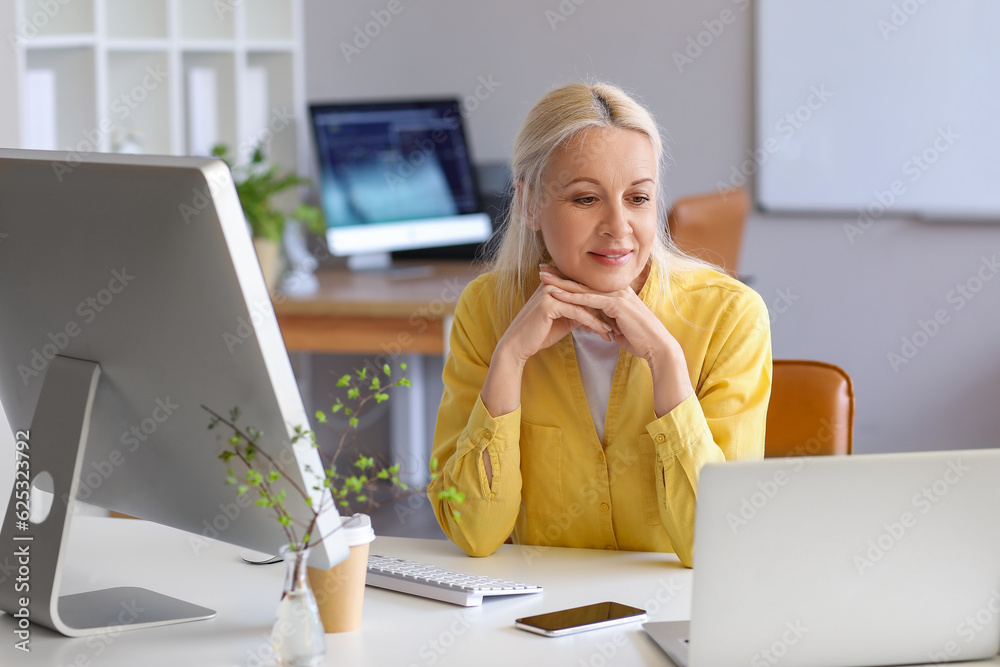 Mature female programmer working at table in office