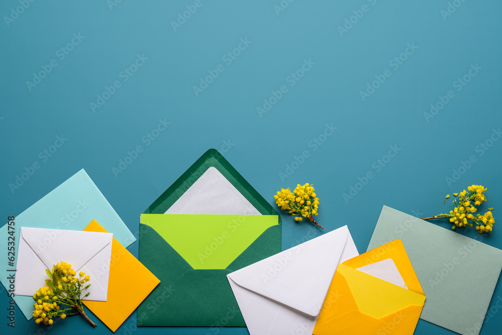 Envelopes with blank cards and blooming plant branches on color background