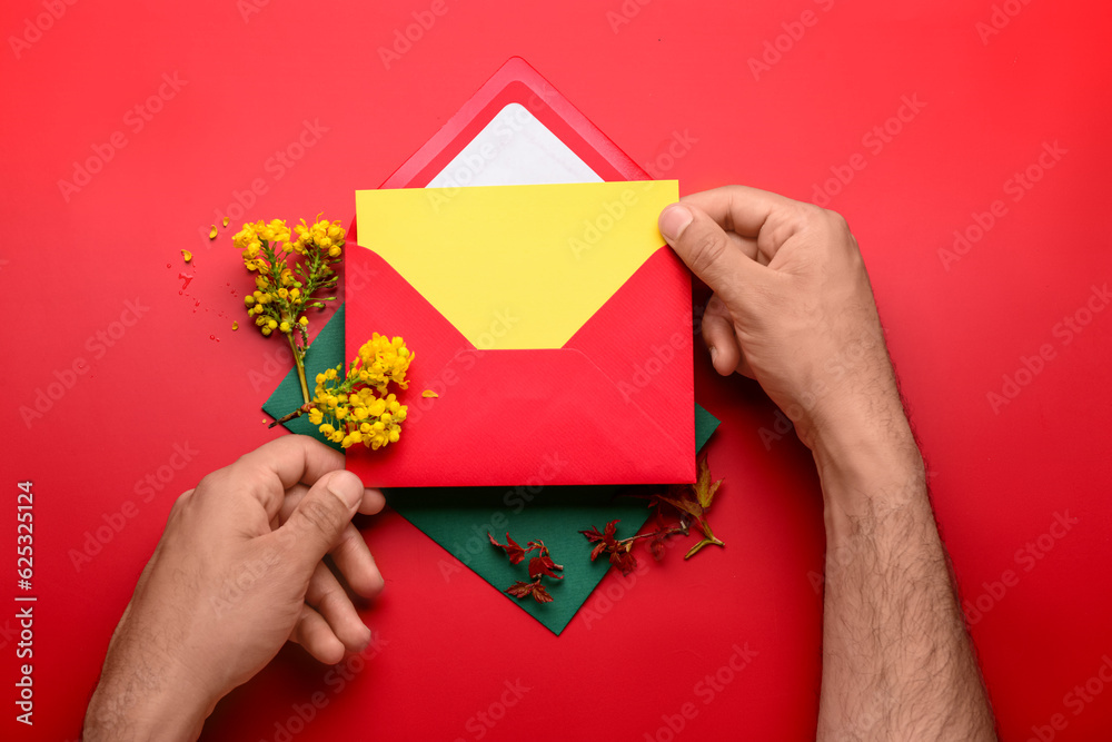 Male hands with envelope, blank card and blooming plant branches on color background, closeup